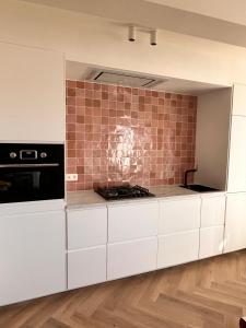 eine Küche mit weißen Schränken und einer gefliesten Wand in der Unterkunft Ostendeau - stijlvol appartement in hartje Oostende in Ostende
