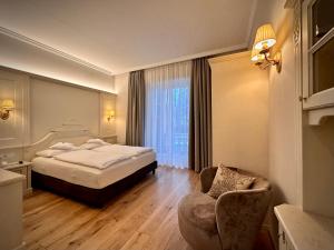 Windsor Merano Hotel & Suites في ميرانو: غرفه فندقيه بسرير وكرسي