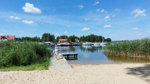 a man walking on a wooden boardwalk next to a river at Dom z balią in Mikołajki