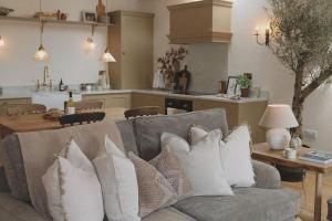 a living room with a couch with pillows and a kitchen at Stock Barn in Youlgreave