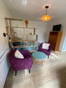 Una sala de estar con dos sillas moradas y una mesa. en Chalet bain nordique - Calm & relax, en Bellême