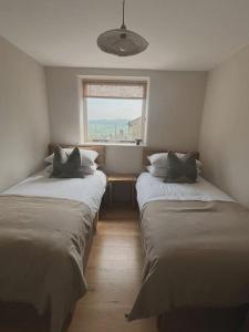 two beds in a small room with a window at Stock Barn in Youlgreave
