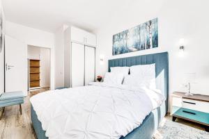 a bedroom with a large white bed with a blue headboard at ARI GREEN Apartment near Atrium Mall in Arad