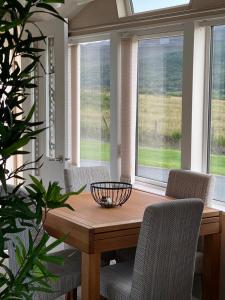 una sala da pranzo con tavolo, sedie e finestre di Caravan Skye Holidays a Portree
