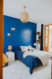 Un dormitorio azul con una cama y una pared azul. en Maison La Pomaré, en Villeneuve-les-Genêts