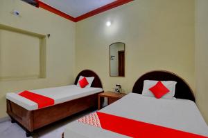 1 Schlafzimmer mit 2 Betten mit roten und weißen Kissen in der Unterkunft OYO Flagship 81231 Urmila Guest House in Bodh Gaya