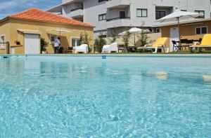 a large blue swimming pool in front of a building at Pontes Guest House in Arcozelo