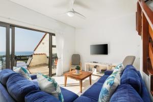 sala de estar con sofá azul y mesa en La Corsica 15, Uvongo, en Margate