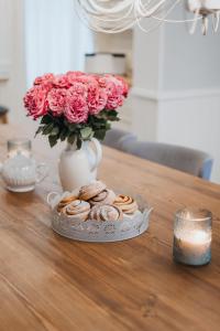 a table with a plate of pastries and a vase with roses at Wiigi Family Home & Spa in Haapsalu +17 photos