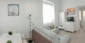 a white living room with a couch and a tv at La Caleta de Cadiz WiFi in Cádiz