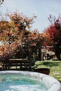 a hot tub in a yard with a bench and trees at Maison La Pomaré in Villeneuve-les-Genêts
