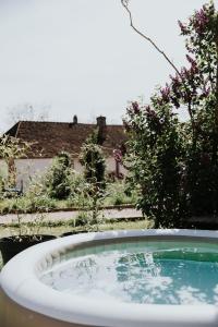 Una bañera en un patio con árboles y una casa. en Maison La Pomaré, en Villeneuve-les-Genêts