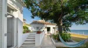 une maison blanche avec un hamac en face d'un arbre dans l'établissement Casa de invitados, a pie de playa, en La Torre Verde, à El Puerto de Santa María