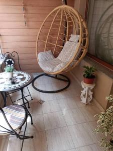 Megi Luxury Apartments في بوموري: شرفة مع كرسي معلق وطاولة