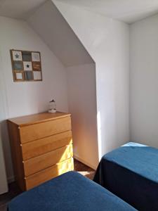 - une chambre avec 2 lits et une commode en bois dans l'établissement Maison au calme, à Camiers