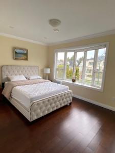 Un dormitorio con una gran cama blanca y una ventana en Coze home in Vancouver near YVR en Vancouver