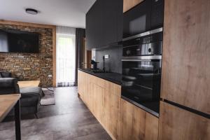 uma cozinha com electrodomésticos pretos e uma parede de tijolos em Luxusní Apartmán Domovjanka - SKALKA FAMILY em Bílá