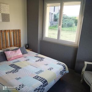 a bedroom with a bed with a quilt and a window at La Clematite d'Olt in Saint-Côme-dʼOlt
