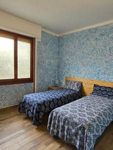 Guest House Fantaccini في Pelago: سريرين في غرفة نوم مع ورق جدران أزرق