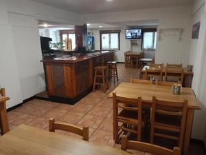 um restaurante com mesas e cadeiras de madeira e um bar em Pension Urola em Zumárraga