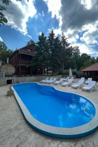 a large blue swimming pool with white lounge chairs at Brvnara Petra in Gornja Toplica