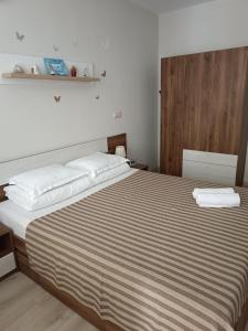 Megi Luxury Apartments في بوموري: غرفة نوم بسرير كبير عليها منشفتين