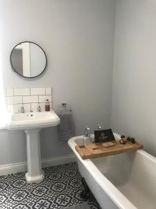 a bathroom with a sink and a tub and a mirror at Billholm House in Bentpath