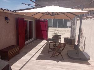 a patio with an umbrella and a table and chairs at Gîte à la ferme in Laudun