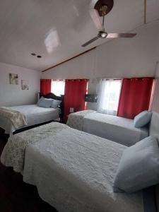 ein Hotelzimmer mit 3 Betten und einem Deckenventilator in der Unterkunft La posada de nana in Alajuela