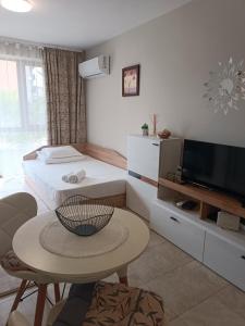 a bedroom with a bed and a table and a tv at Megi Apartments, Nesebar sity in Nesebar