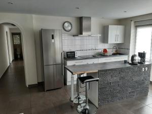 a kitchen with a stainless steel refrigerator and a clock on the wall at Appart cosy aux écluses du port in Morlaix +6 photos