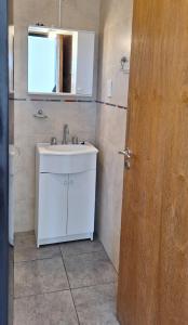 a bathroom with a sink and a mirror and a door at Departamento familiar in Caleta Olivia