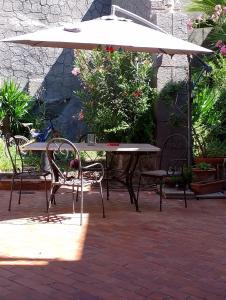 una mesa y sillas bajo una sombrilla en un patio en Casa Romeo, en Adrano