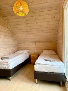 2 łóżka w pokoju z drewnianymi ścianami w obiekcie Słonecznikowa Dolina w Sarbinowie