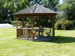 a wooden gazebo with a picnic table in the grass at Les Baillis in Villegenon