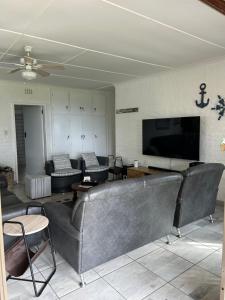 a living room with couches and a flat screen tv at Meet U at the Beach in Hibberdene