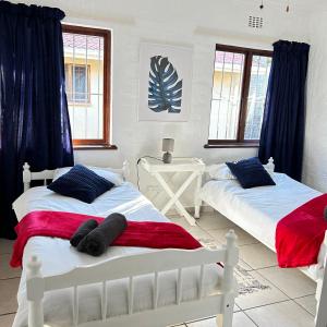two white beds in a room with two windows at Meet U at the Beach in Hibberdene