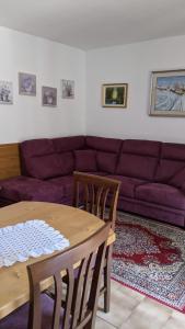 - un salon avec une table et un canapé violet dans l'établissement Auronzo Vacanze di Marina e Valter - Corte 25, à Auronzo di Cadore