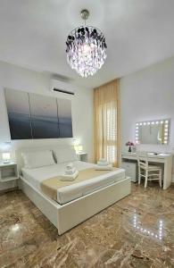 a large white bedroom with a large bed and a chandelier at Albatros B&B Porto Cesareo in Porto Cesareo
