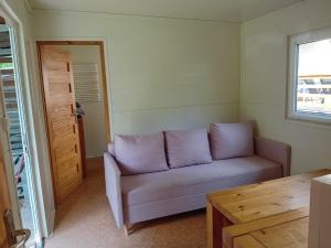 - un salon avec un canapé violet et une table dans l'établissement Domek 2, à Dębki