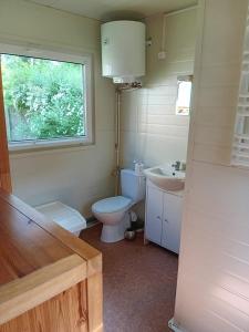 La salle de bains est pourvue de toilettes, d'un lavabo et d'une fenêtre. dans l'établissement Domek 2, à Dębki