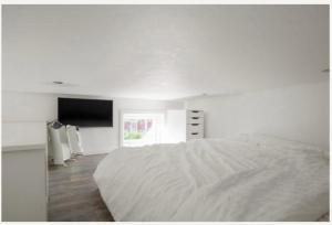 a white bedroom with a bed and a flat screen tv at Fresh happy little house, 35 m2 IN Täby in Stockholm