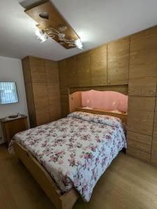 - une chambre avec un grand lit et une couette rose dans l'établissement Auronzo Vacanze di Marina e Valter - Corte 25, à Auronzo di Cadore