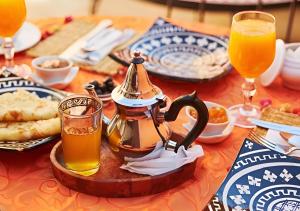 a table with a tea pot and glasses of orange juice at Merzouga Top Desert Camp in Merzouga