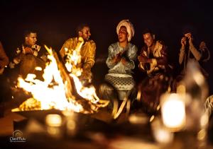 a group of people sitting around a fire at Merzouga Top Desert Camp in Merzouga