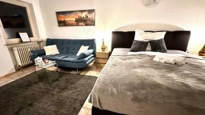 a bedroom with a large bed and a blue couch at BeeFree Thermen und Golf3 I Free Parking I Balcony in Pocking