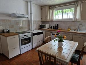 a kitchen with a table with a vase of flowers on it at Maison du Coucou in Larbey