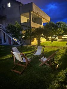 two chairs sitting in the grass in front of a house at Apartmani Zelenika in Herceg-Novi