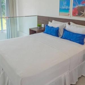 a large white bed with blue pillows in a bedroom at The Coral Beach Resort by Atlantica in Trairi