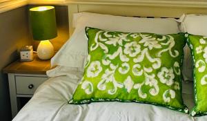 a bed with a green and white pillow and a lamp at Bettys in Hunstanton